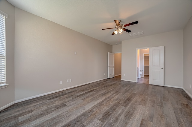 unfurnished bedroom with multiple windows, hardwood / wood-style flooring, a walk in closet, and ceiling fan