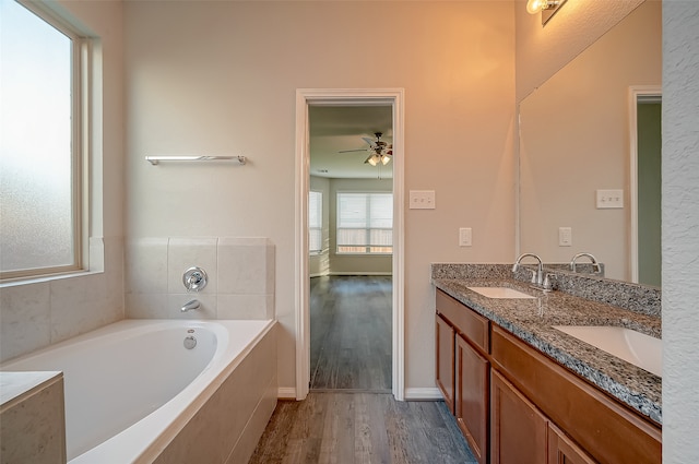 bathroom with vanity, ceiling fan, wood-type flooring, and a relaxing tiled tub