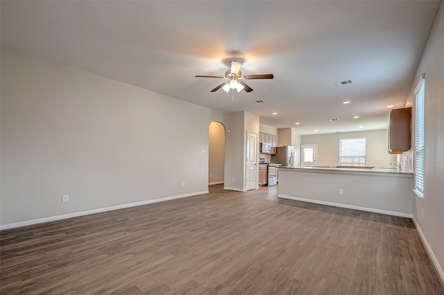 unfurnished living room featuring hardwood / wood-style flooring, sink, and ceiling fan