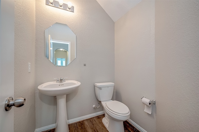 bathroom featuring wood-type flooring, toilet, and vaulted ceiling