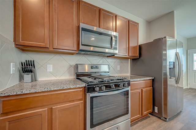 kitchen featuring light wood-type flooring, appliances with stainless steel finishes, and decorative backsplash