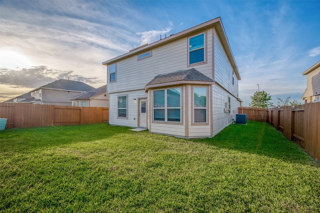 rear view of house with a lawn and central AC unit