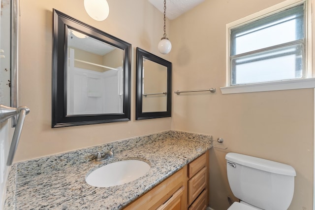 bathroom featuring vanity, a shower, toilet, and a textured ceiling