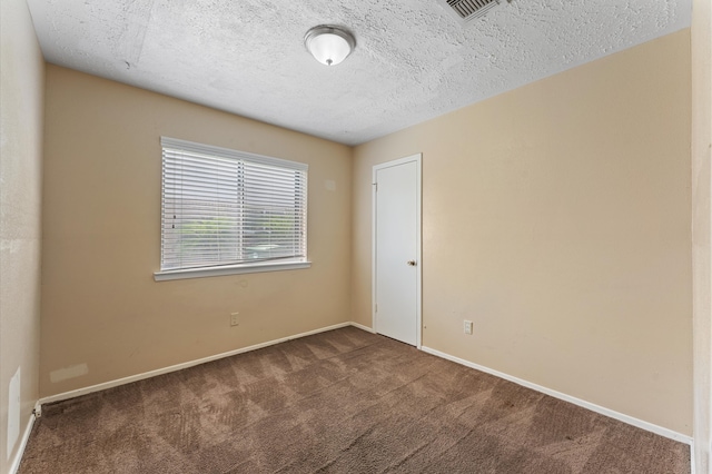 empty room featuring dark carpet and a textured ceiling