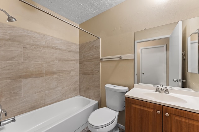 full bathroom with a textured ceiling, tiled shower / bath combo, vanity, and toilet