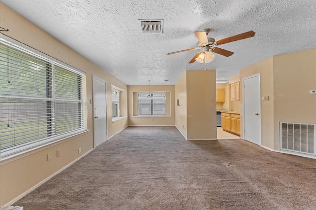 unfurnished room featuring light carpet, ceiling fan, and a textured ceiling