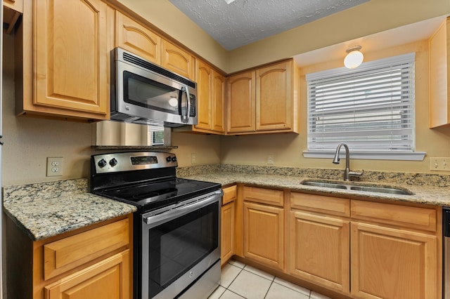 kitchen with light stone counters, a textured ceiling, appliances with stainless steel finishes, and sink