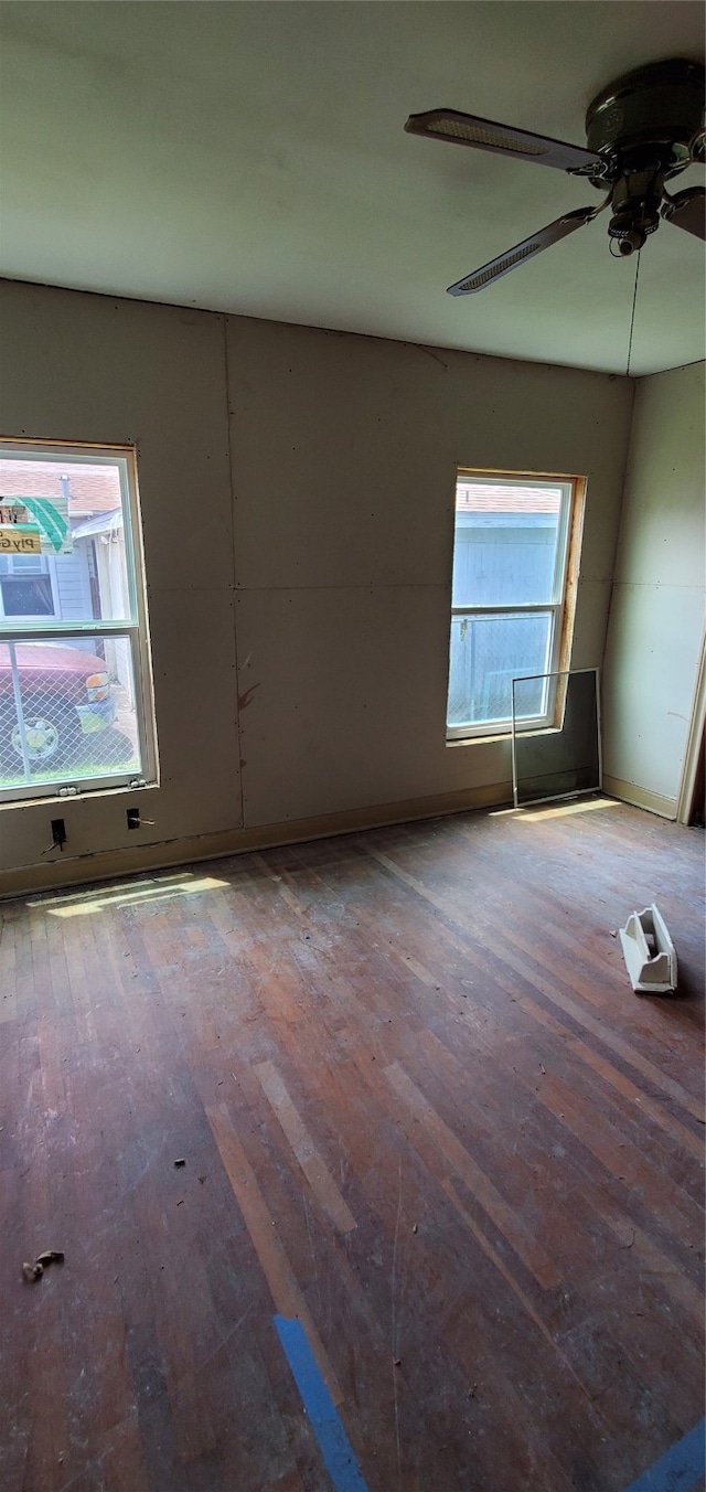 spare room featuring ceiling fan, hardwood / wood-style flooring, and a healthy amount of sunlight