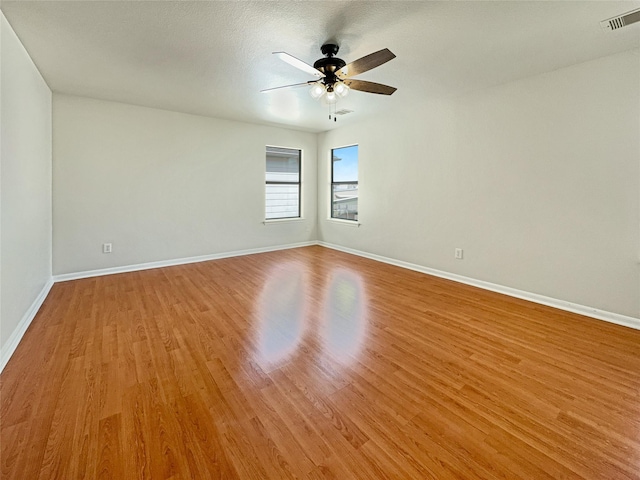 unfurnished room with visible vents, ceiling fan, light wood-style flooring, and baseboards