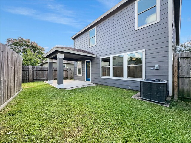 rear view of property featuring cooling unit, a lawn, and a patio