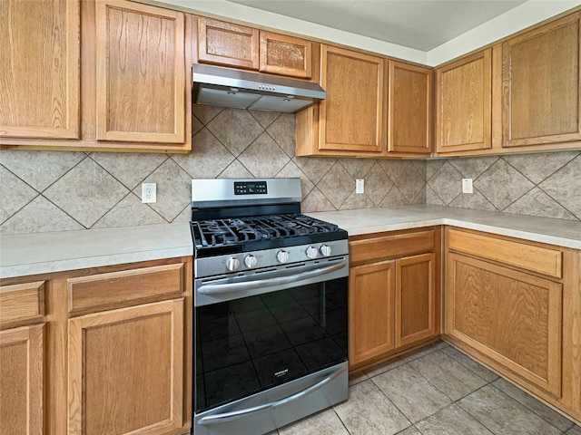 kitchen with light tile patterned floors, backsplash, and gas stove