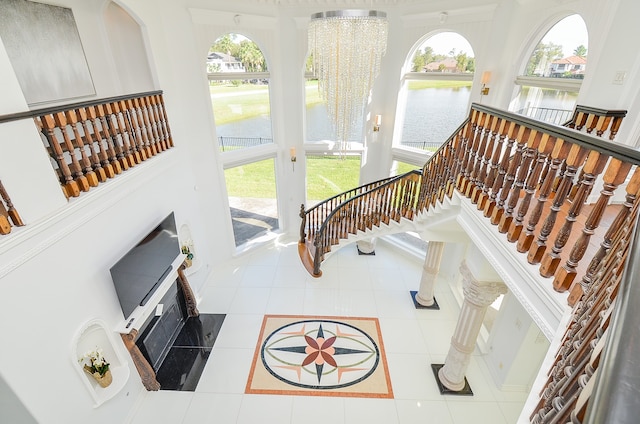 living room featuring a water view, plenty of natural light, a chandelier, and tile patterned floors