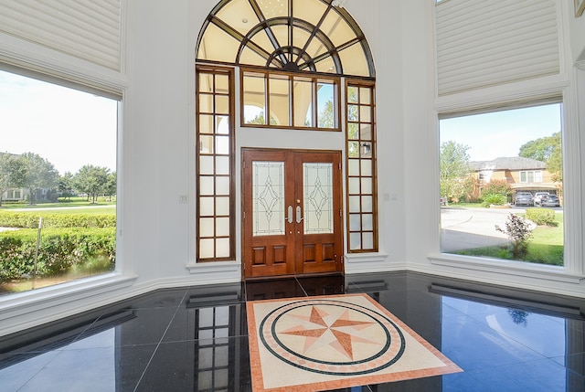 entrance foyer with a high ceiling, a wealth of natural light, and french doors