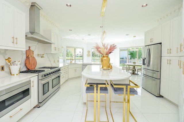 kitchen featuring backsplash, stainless steel appliances, light stone counters, wall chimney exhaust hood, and light tile patterned flooring