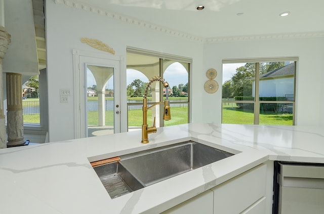 kitchen featuring white cabinetry, a healthy amount of sunlight, sink, and light stone countertops