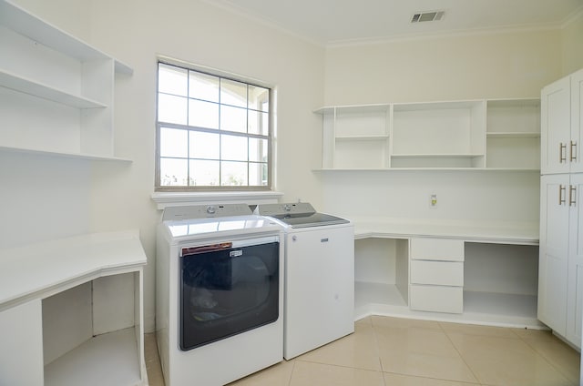 laundry area with light tile patterned floors, washing machine and clothes dryer, cabinets, and ornamental molding