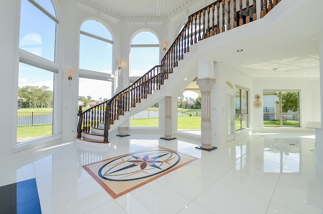 interior space featuring a towering ceiling, tile patterned floors, and a water view