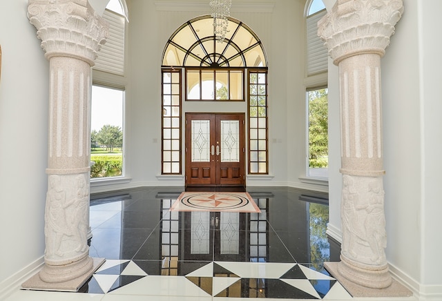 foyer featuring a towering ceiling and decorative columns