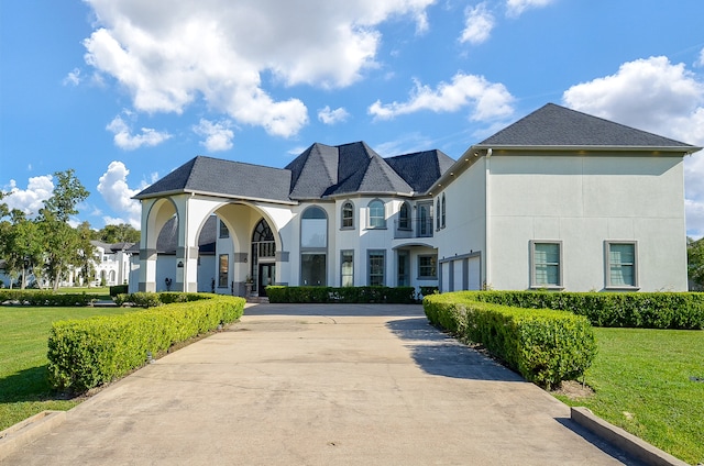 view of front of house featuring a balcony and a front lawn