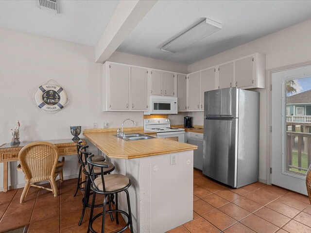 125 Driftwood Ct, Surfside Beach, TX 77541 - kitchen featuring visible vents, a sink, light tile patterned floors, and white appliances