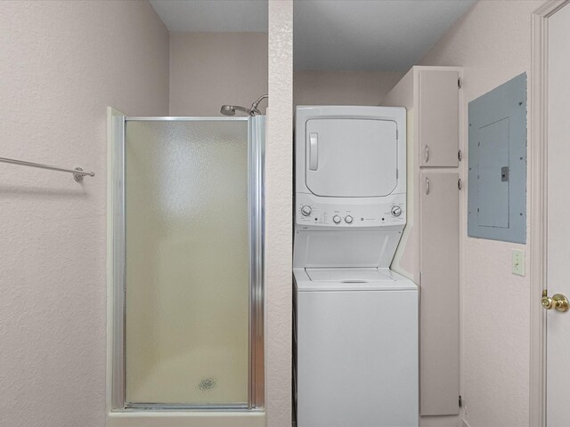 clothes washing area with stacked washer and clothes dryer and electric panel