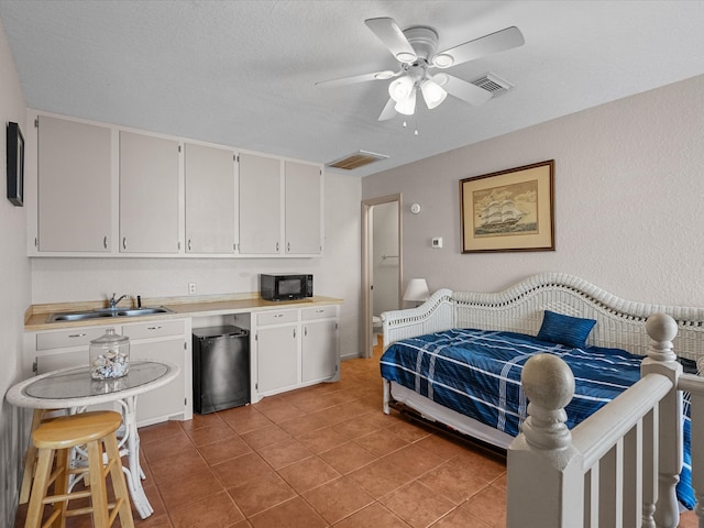 tiled bedroom with fridge, sink, a textured ceiling, and ceiling fan