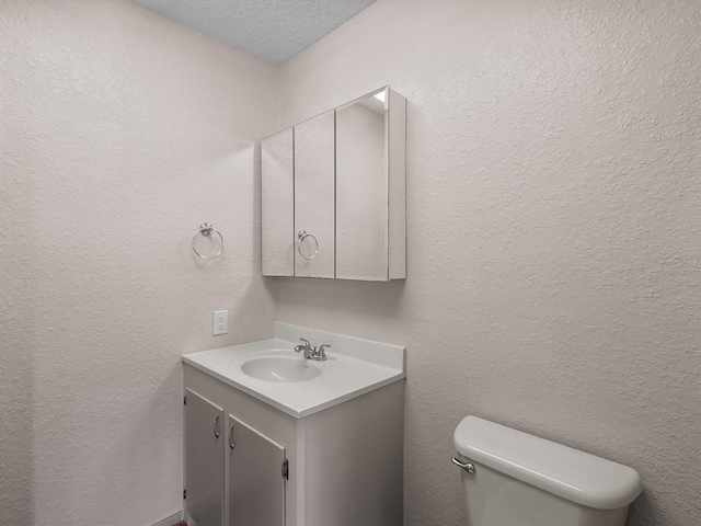 bathroom featuring toilet, vanity, and a textured ceiling