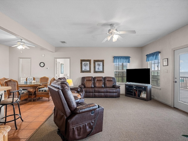 living room with a textured ceiling, ceiling fan, and light tile patterned floors