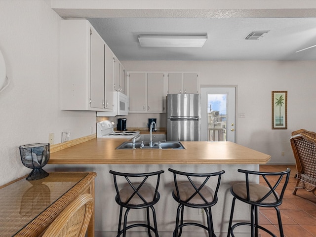 125 Driftwood Ct, Surfside Beach, TX 77541 - kitchen featuring visible vents, a peninsula, white appliances, white cabinetry, and a sink