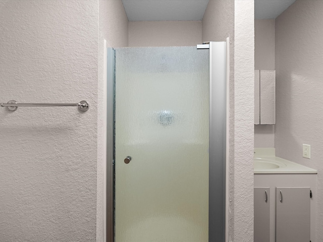 bathroom featuring a shower with shower door and vanity