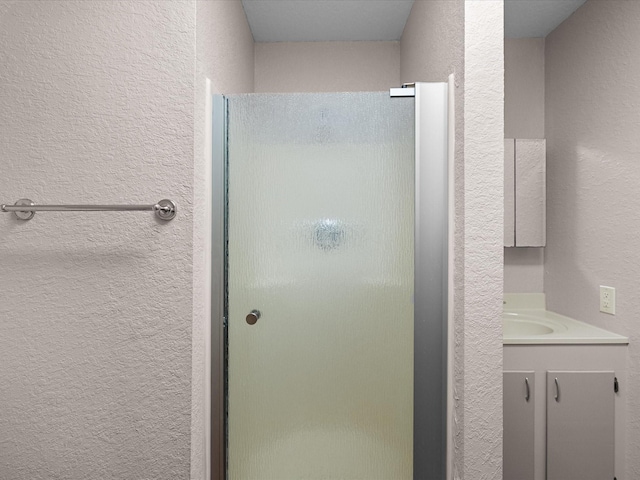 125 Driftwood Ct, Surfside Beach, TX 77541 - bathroom featuring vanity, a textured wall, and a stall shower