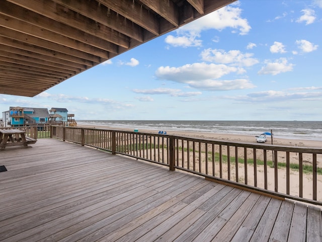 wooden terrace featuring a view of the beach and a water view