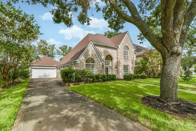 view of front of house featuring brick siding, a detached garage, and a front yard