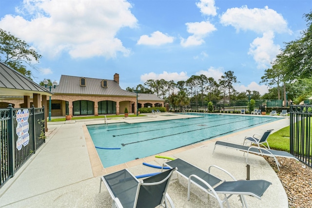 community pool with a patio area and fence