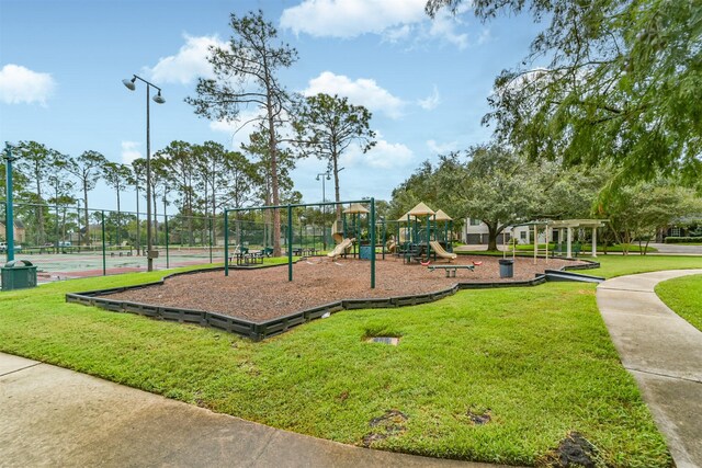 communal playground featuring a yard and fence