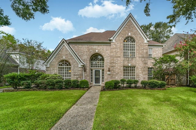 view of front of home featuring brick siding, a shingled roof, and a front lawn