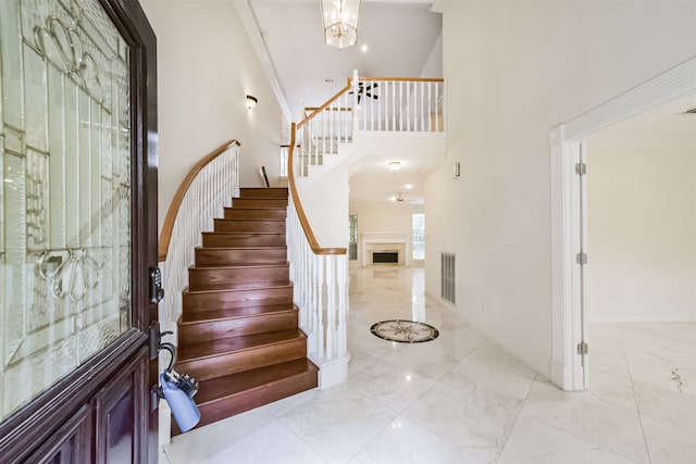 foyer with crown molding, a towering ceiling, and a chandelier