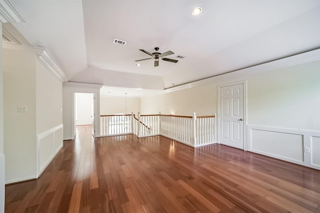 spare room featuring visible vents, wood finished floors, a decorative wall, and a ceiling fan