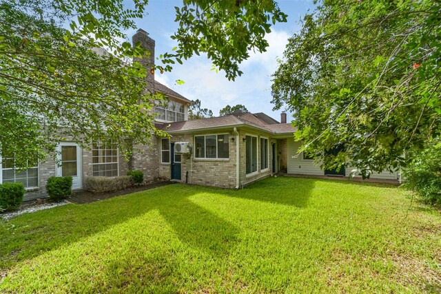 back of property with a yard, brick siding, and a chimney