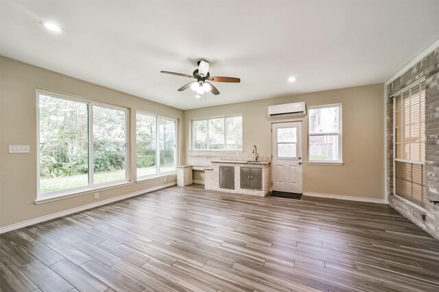 unfurnished living room featuring recessed lighting, baseboards, dark wood-type flooring, and a wall mounted AC