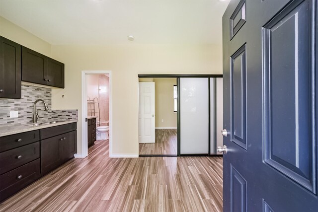 kitchen with baseboards, light wood finished floors, a sink, light countertops, and tasteful backsplash