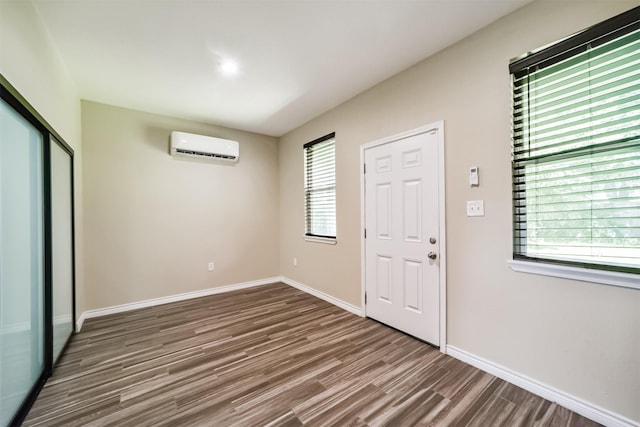 foyer entrance featuring baseboards, wood finished floors, and a wall mounted air conditioner