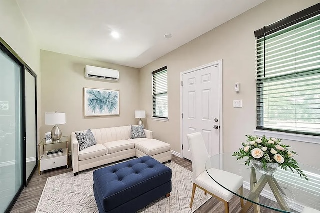 living area featuring baseboards, wood finished floors, and a wall mounted AC