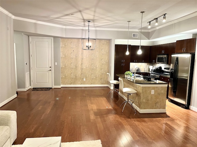 kitchen featuring hardwood / wood-style floors, appliances with stainless steel finishes, an island with sink, a breakfast bar, and dark brown cabinetry