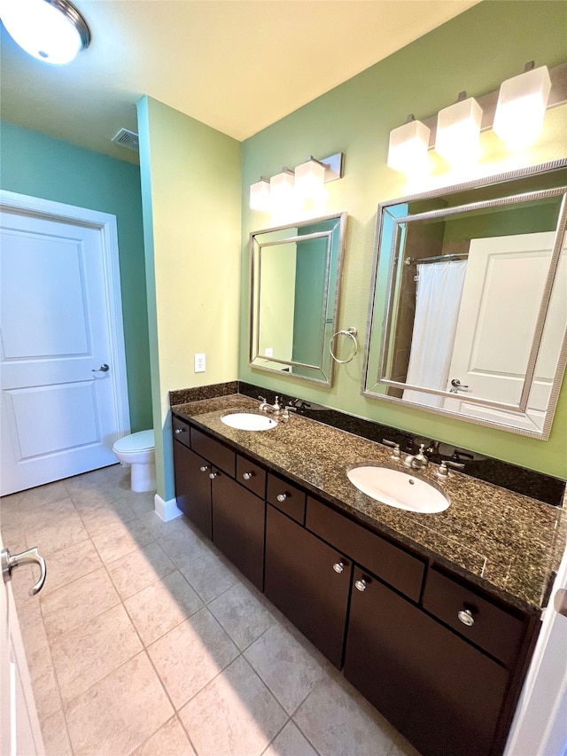 bathroom with tile patterned flooring, vanity, and toilet