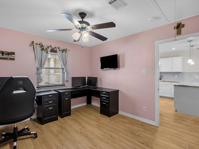 office space featuring light wood finished floors, attic access, visible vents, baseboards, and a ceiling fan