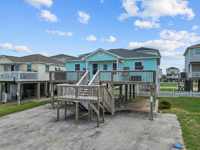 back of house featuring a carport, roof with shingles, a wooden deck, and a residential view