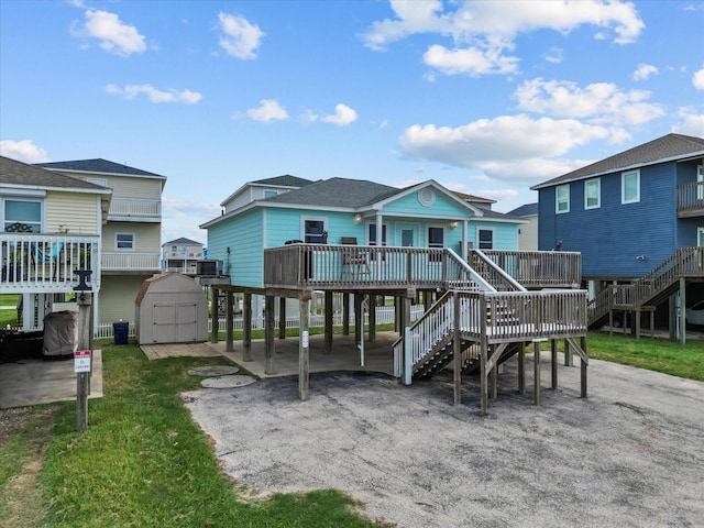 back of property with an outbuilding, a storage unit, a deck, a carport, and stairs