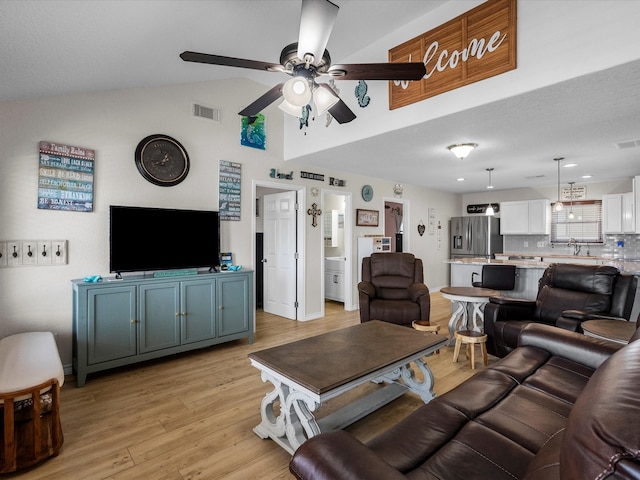 living room with vaulted ceiling, ceiling fan, and light hardwood / wood-style flooring