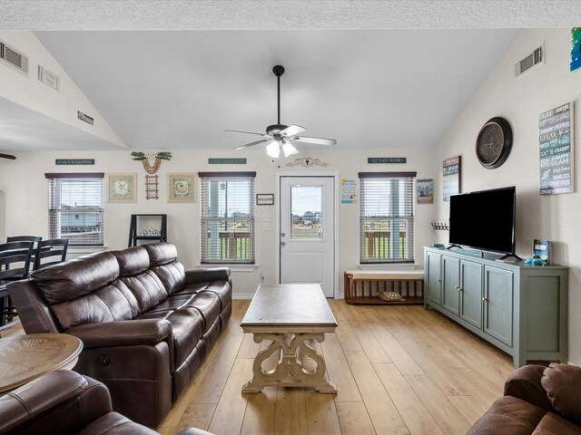 living room with a textured ceiling, vaulted ceiling, ceiling fan, and light hardwood / wood-style flooring